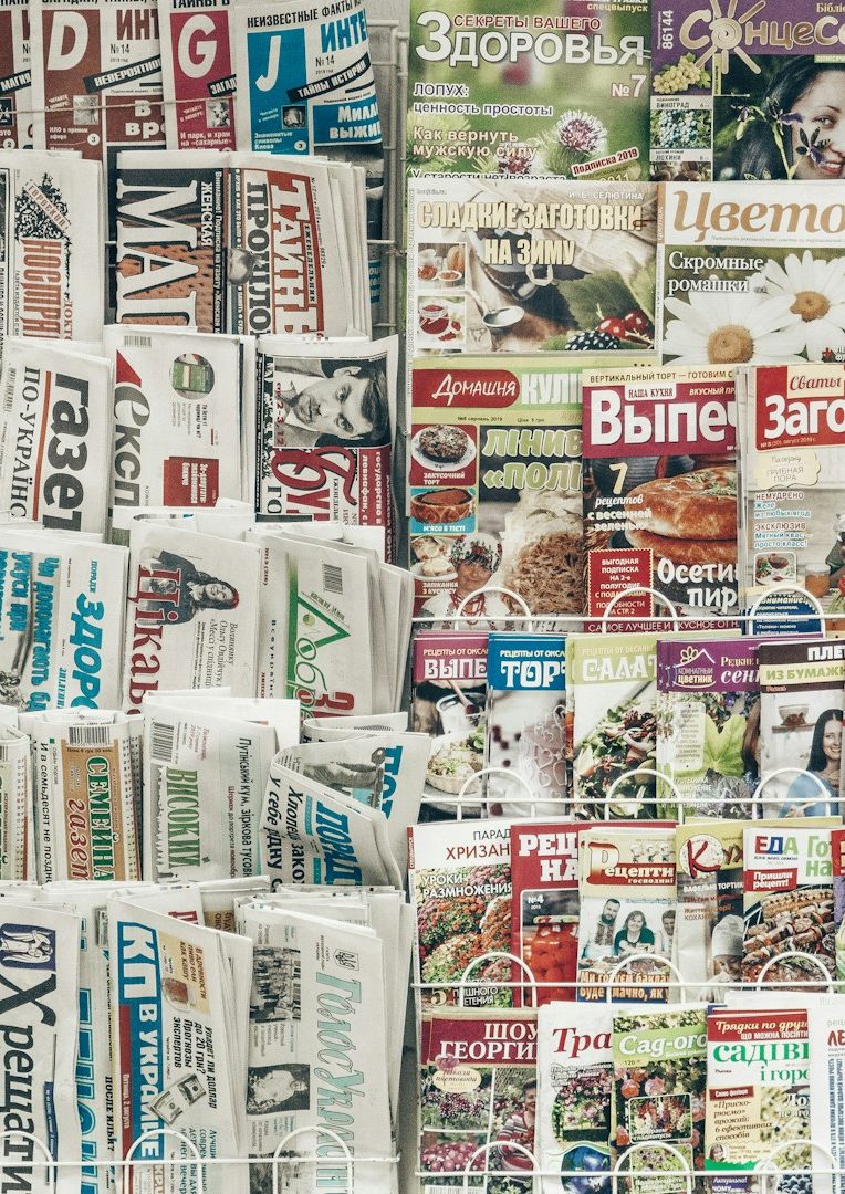 Verschiedene Zeitungen und Magazine übereinander gestapelt, bunt bedruckte Seiten.