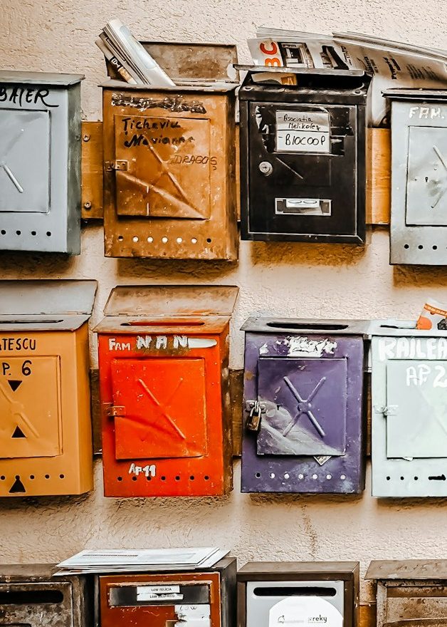 Bunte Briefkästen in verschiedenen Größen und Farben an einer Wand.