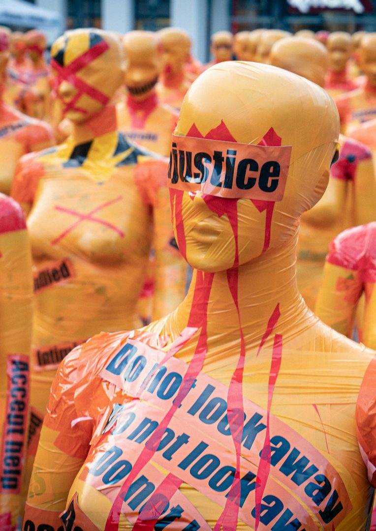 Gelbe Mannequins mit roten und schwarzen Schriftzügen für Gerechtigkeit und Protest.